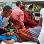 Medical workers and other Somalis help a woman who was wounded when a powerful car bomb blew off the security gates to the Elite .