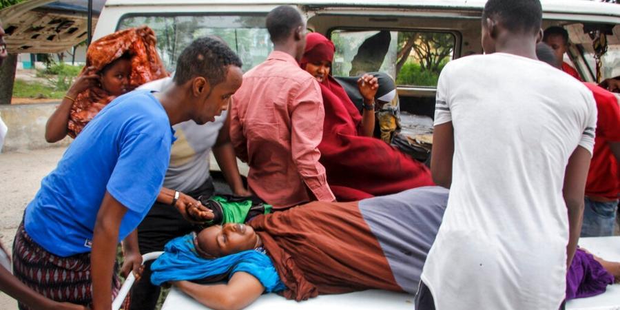Medical workers and other Somalis help a woman who was wounded when a powerful car bomb blew off the security gates to the Elite .