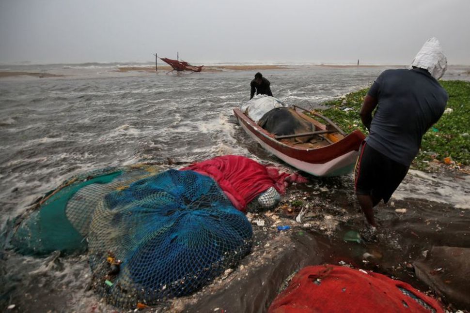 Fishermen move a fishing boat to a safer place along the shore before Cyclone Nivar's landfall, in Chennai, India, November 25, 2020.